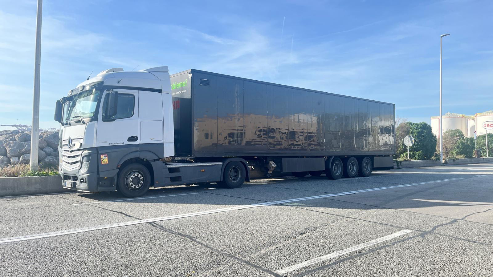 Weisser Mercedes Sattelzug mit dunklem Anhaenger auf einem Parkplatz