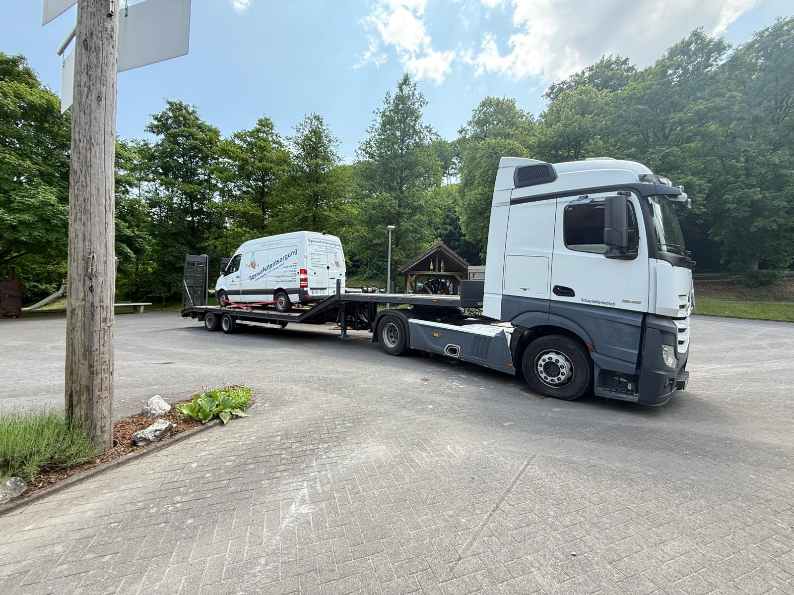 Weisser Autotransporter mit aufgeladenem Transporter auf gepflastertem Parkplatz