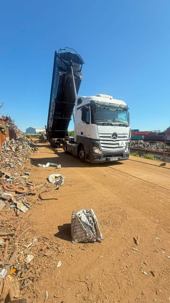 Weisser Sattelschlepper mit gekippter Mulde entlaedt Schrott auf Recyclinghof